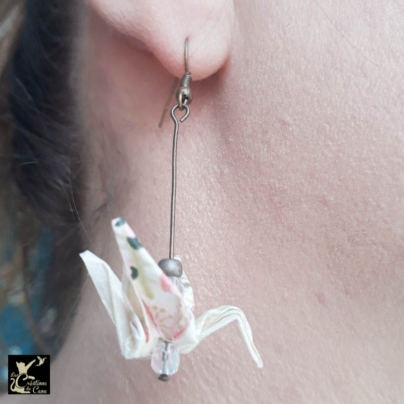 Boucles d'oreilles en origami. Le pliage est une grue traditionnelle réalisée à partir d'un papier japonais écru au motif fleuri rose poudré.