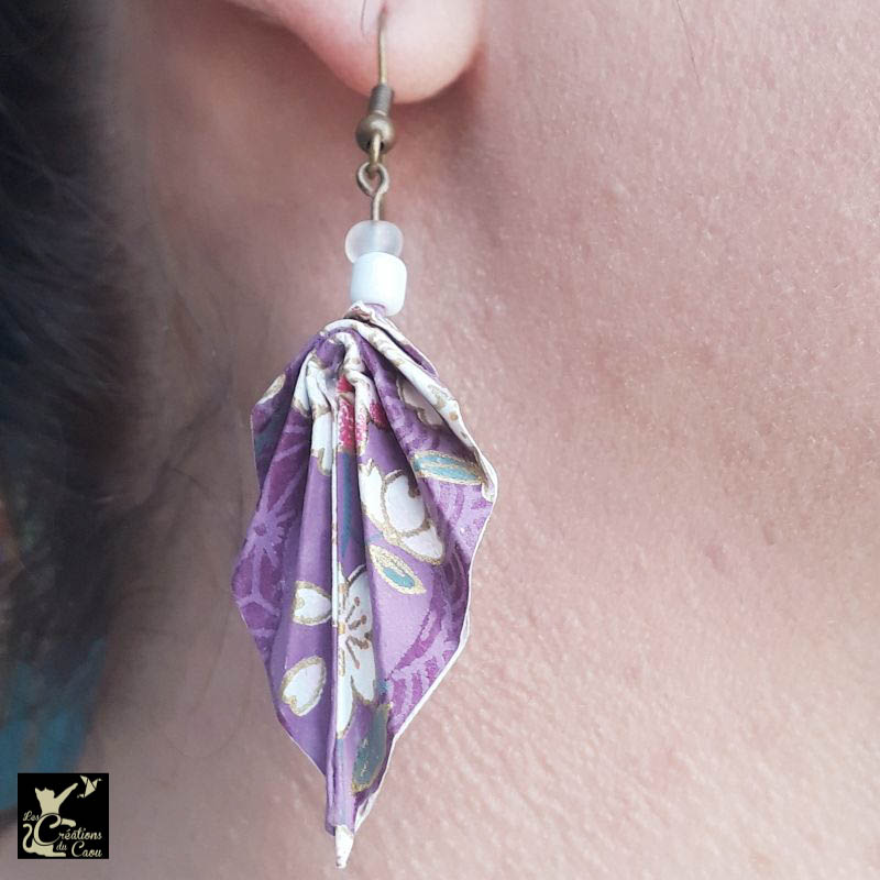 Boucles d'oreilles en origami. Le pliage est une palme réalisée à partir d'un papier japonais violet au motif fleuri de sakuras (fleurs de cerisiers) roses et blancs. Le papier est recouvert de résine afin de rigidifier et protéger le pliage.