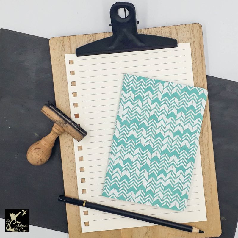 Carnet de notes au format A6. La couverture est recouverte à la main d’un papier indien bleu turquoise sur lequel sont dessinés des chevrons blancs.