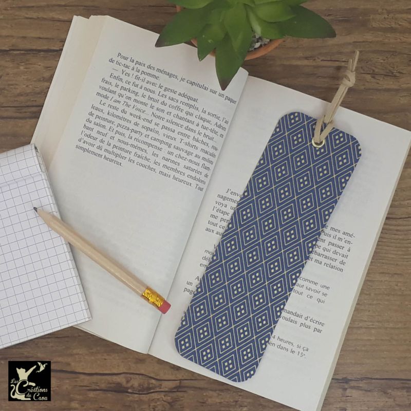 Ne perdez plus le fil de vos lectures ! Ce marque-page artisanal, recouvert d'un élégant papier japonais bleu foncé orné de losanges dorés deviendra votre allié.