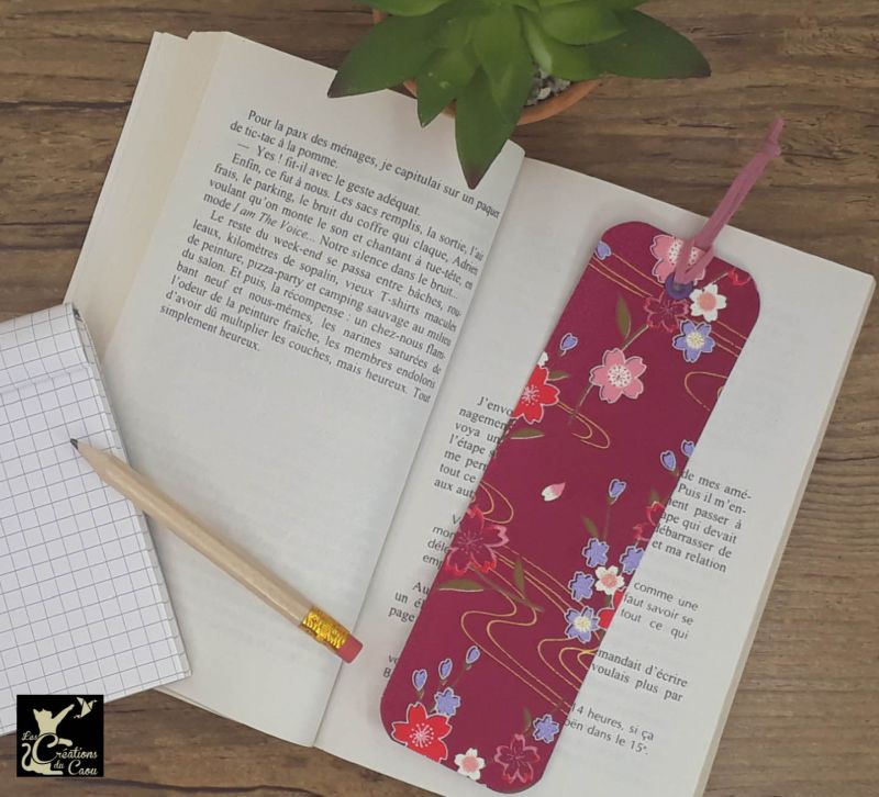 Ne perdez plus le fil de vos lectures ! Ce marque-page artisanal, recouvert d'un élégant papier japonais fuchsia orné de fleurs deviendra votre allié.