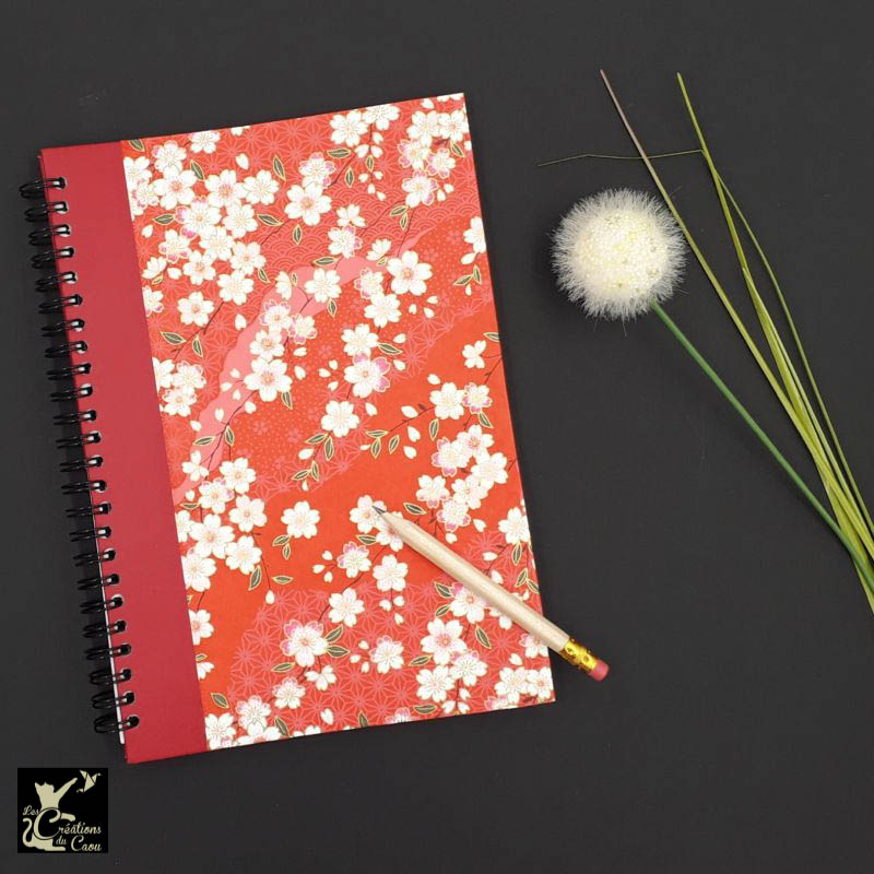 Répertoire à spirale recouvert d'un papier artisanal au motif de sakura sur fond rouge.