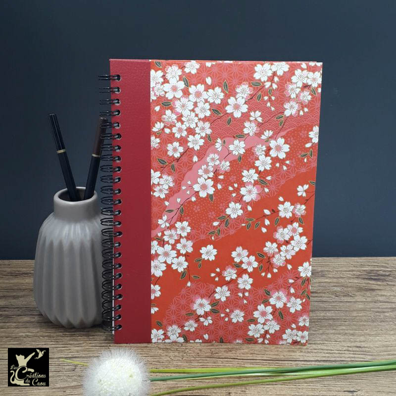 Répertoire à spirale recouvert d'un papier artisanal au motif de sakura sur fond rouge.