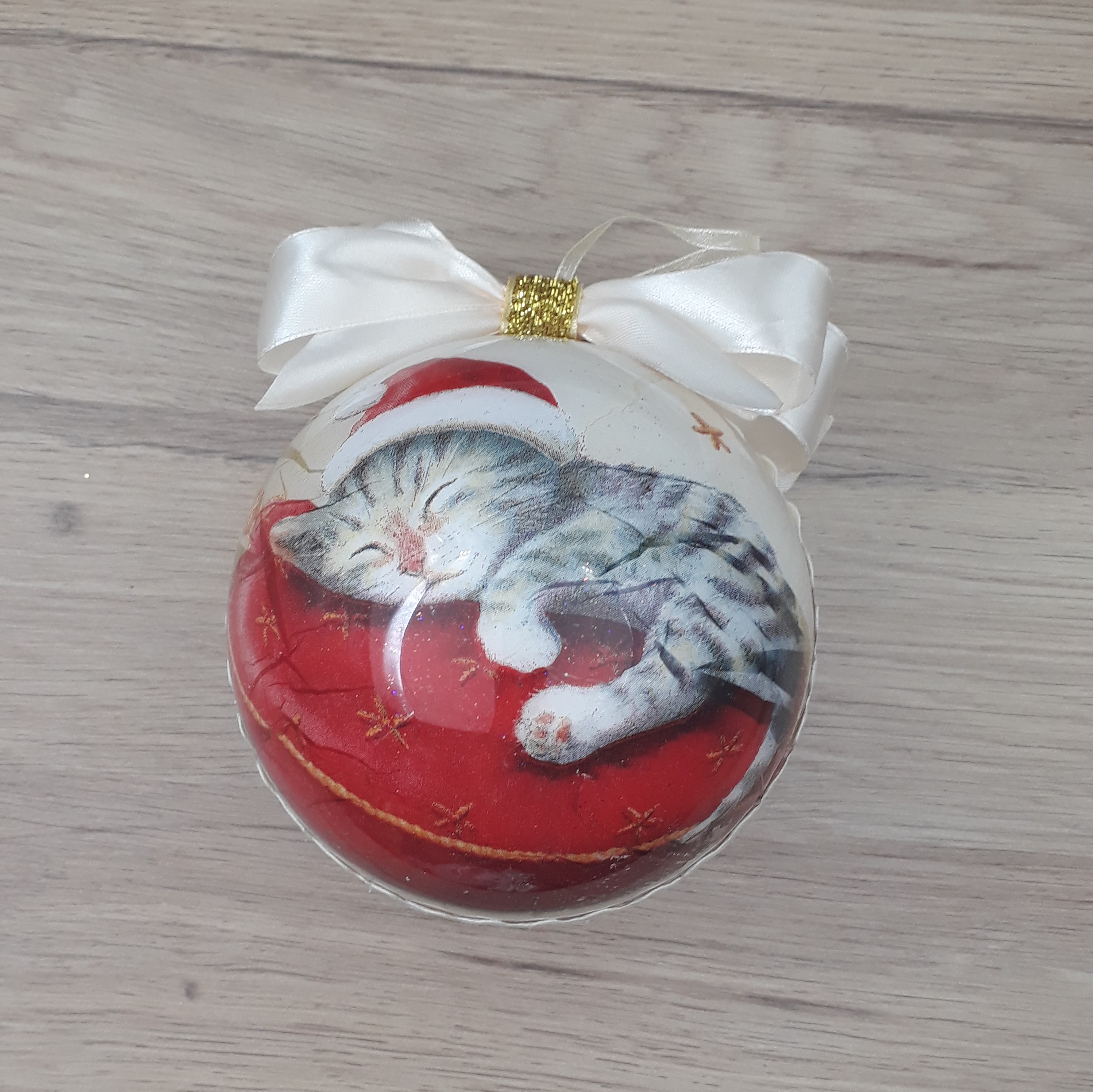 Grande boule décorée à la main au motif de chat endormi sur un coussin.