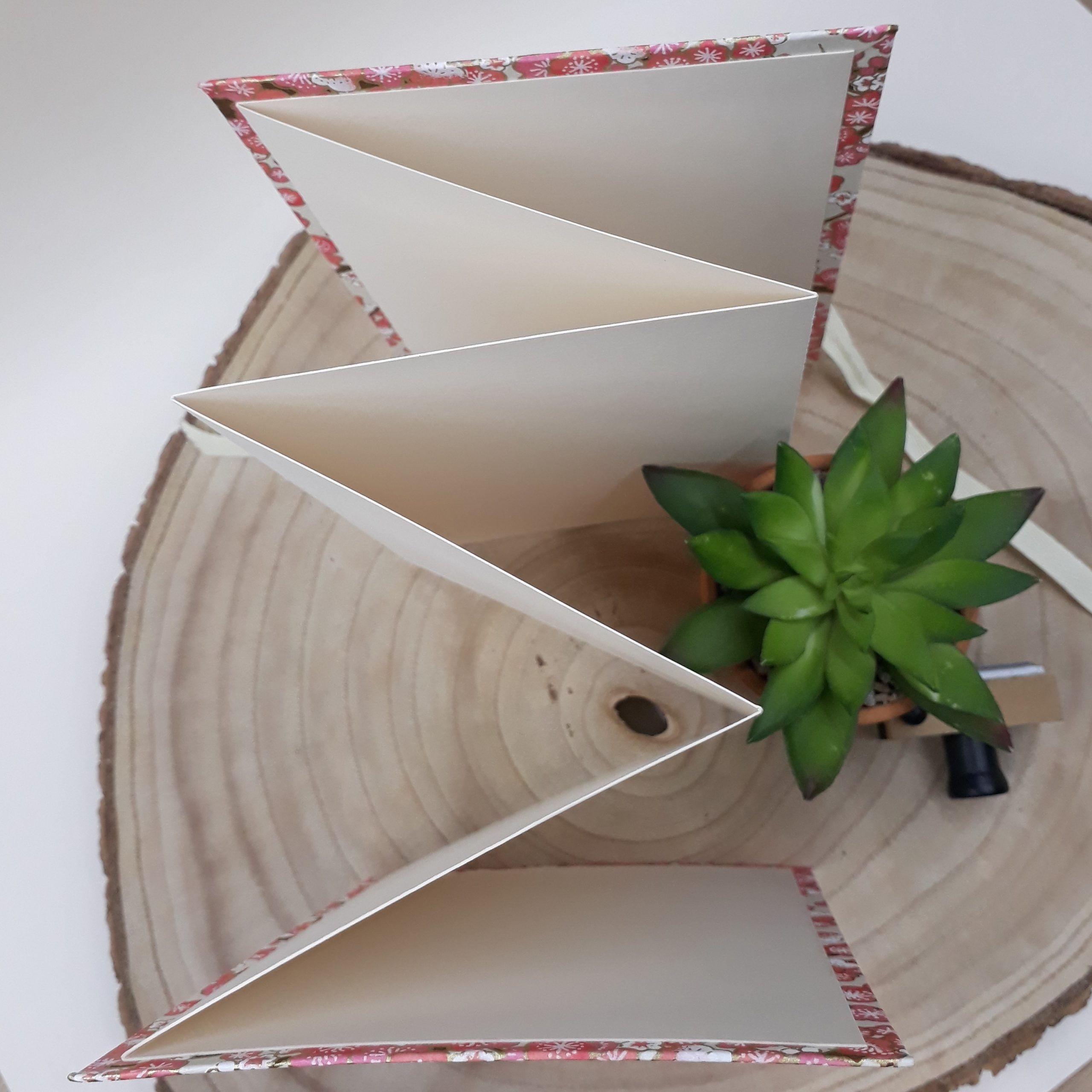 Album photo leporello réalisé à la main dans notre atelier de Lambersart (Lille), recouvert d'un papier japonais écru au motif de fleurs de pruniers roses.