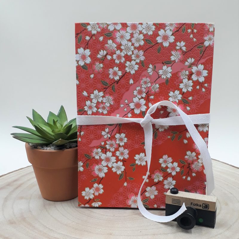 Album photo leporello réalisé à la main dans notre atelier de Lambersart (Lille), recouvert d'un papier japonais rouge au motif de fleurs de cerisiers (sakura) blanches.