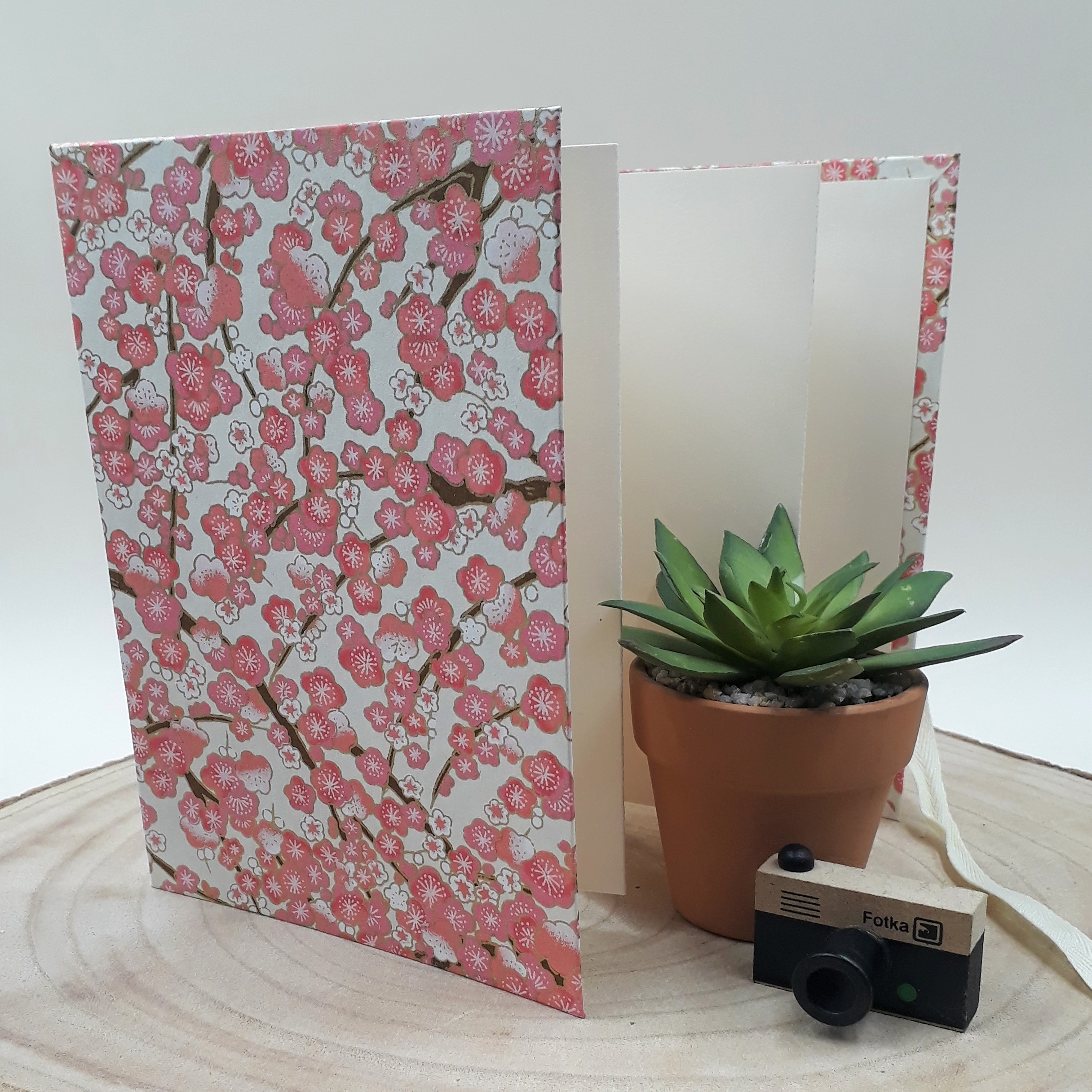 Album photo leporello réalisé à la main dans notre atelier de Lambersart (Lille), recouvert d'un papier japonais écru au motif de fleurs de pruniers roses.