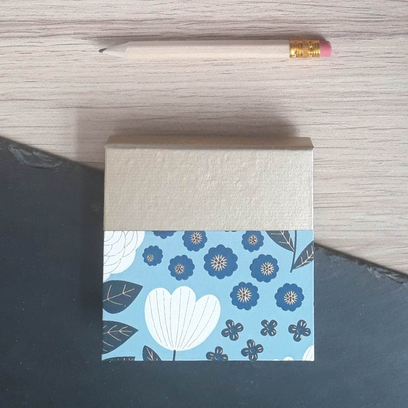 Porte bloc à post-it de la marque de papeterie lilloise : les créations du caou. Papier japonais bleu ciel, fleurs stylisées bleues et blanches.