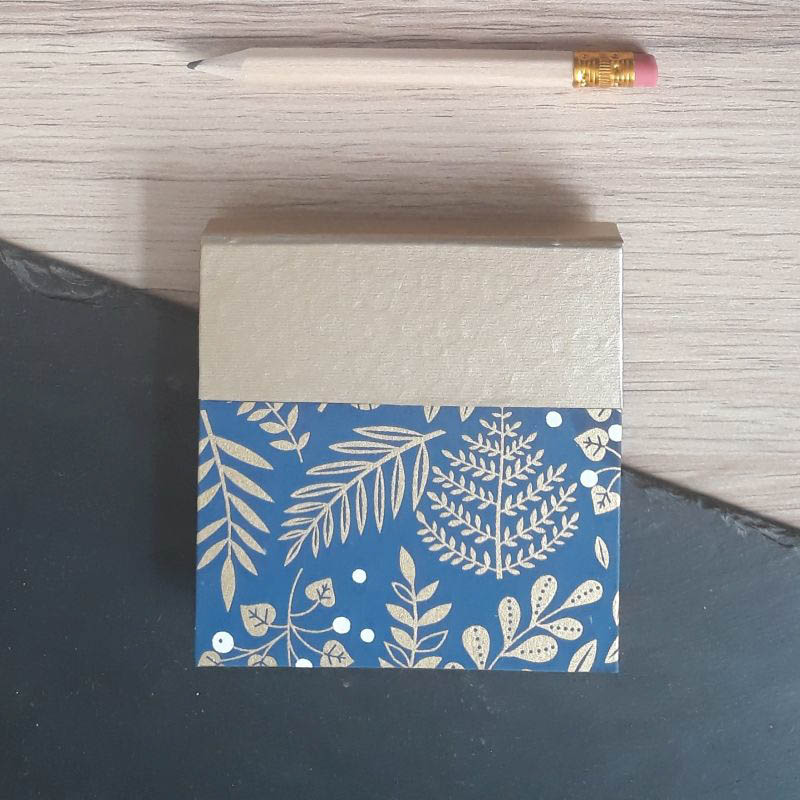 Porte bloc à post-it de la marque de papeterie lilloise : les créations du caou. Papier japonais bleu foncé, motifs de végétaux dorés.