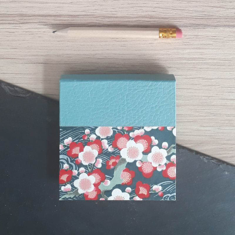 Porte bloc à post-it de la marque de papeterie lilloise : les créations du caou. Motif fleuri sur fond bleu pétrole.