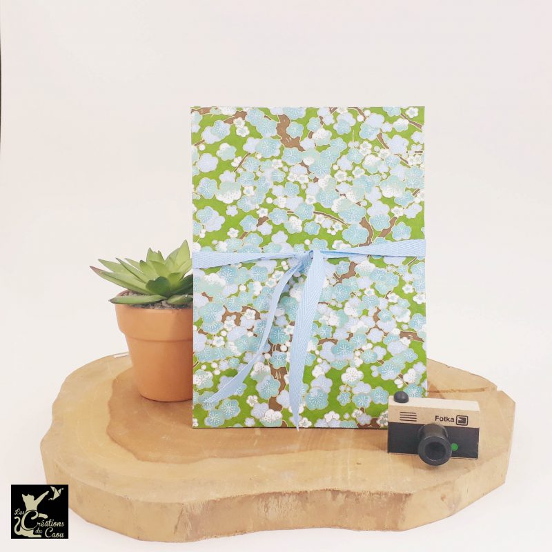 Album photo leporello réalisé à la main dans notre atelier de Lambersart (Lille), recouvert d'un papier japonais vert printemps au motif de fleurs de prunier blanches et bleues.