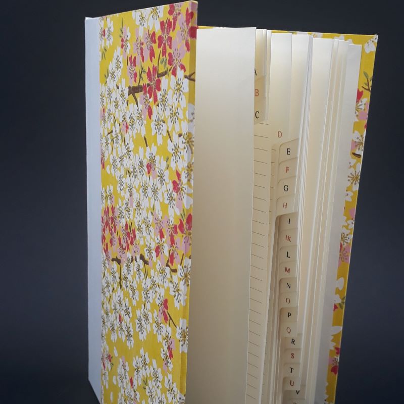 Répertoire ou carnet d'adresses jaune, motif fleuri, à onglet, dos carré collé.